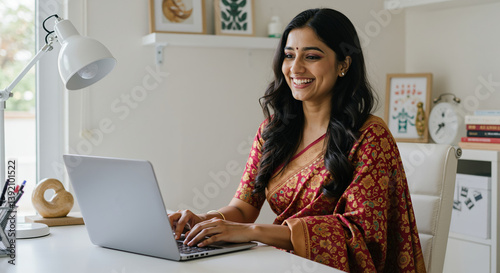 Happy Indian woman in a saree working on her laptop from home office 