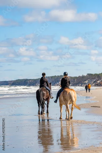 Fototapeta na wymiar Obozy jeździeckie i jazda konno po plaży zamiast typowych wakacji nad polskim morzem. Nauka jeździectwa nad Bałtykiem. Jazda zastępem.