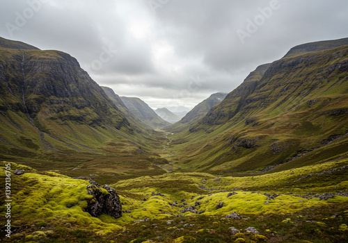 Mountain Valley Landscape with Green Moss and Cloudy Sky in Scotland. The mountain valley is surrounded by mountains with a river running through it under cloudy sky