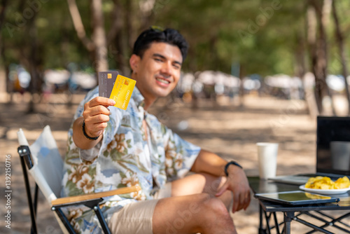 Happy Asian man travel nature the sea on summer beach holiday vacation. Portrait of Handsome guy in beach clothing holding credit card during relaxing on tropical island beach in sunny day.