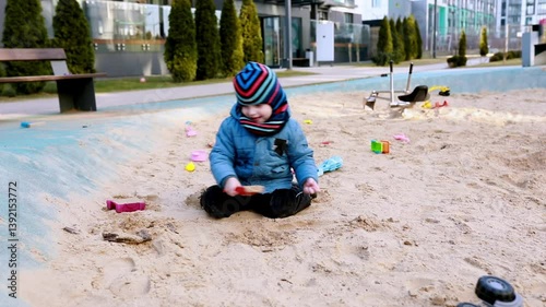 Young child plays in sand at a modern playground on a sunny day enjoying outdoor fun and creativity