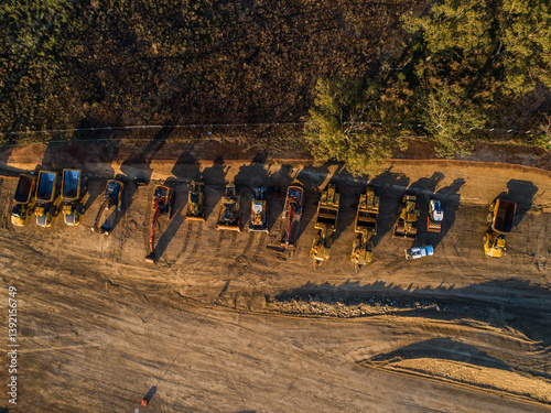 Machinery on worksite lined up in morning light ready to continue construction on bypass road