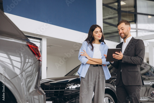 Foto Young woman customer female buyer client wears shirt consult with salesman hold tablet choosing auto want to buy new automobile in car showroom vehicle salon dealership store motor show