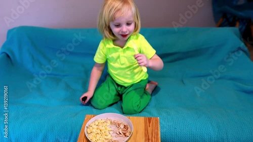 Child enjoying meal on couch with wooden tray in cozy living room