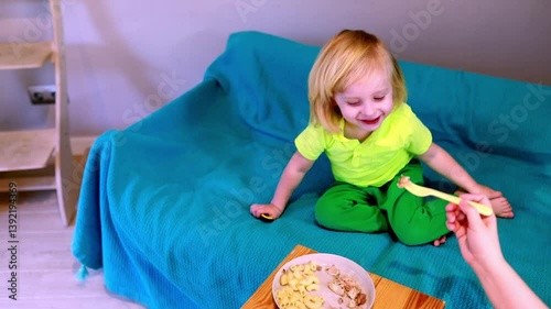 Child enjoys relaxing on a couch while playing with a toy and eating snacks at home