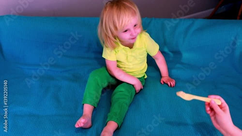 Young child plays on colorful blanket in living room while adorable puppy watches nearby
