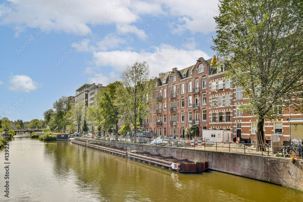 A picturesque view of a canal lined with trees and historic buildings, showcasing a vibrant urban landscape with boats and clear blue skies. A picturesque view of a canal lined with trees and historic buildings, showcasing a vibrant urban landscape with boats and clear blue skies.