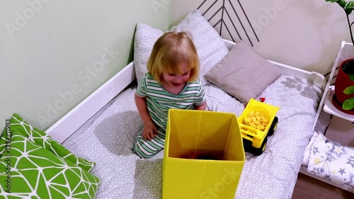 Child plays with yellow boxes and a toy truck in a cozy indoor play area