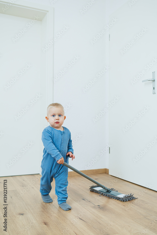 Little boy helper cleaning at home. Blond toddler boy washes the floor with a mop, helping his mother clean at home, free space. Child learns to clean the house.