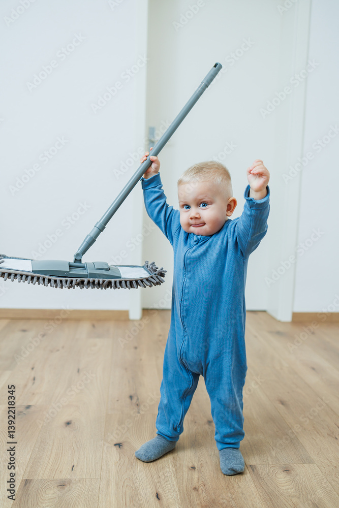 Little boy helper cleaning at home. Blond toddler boy washes the floor with a mop, helping his mother clean at home, free space. Child learns to clean the house.