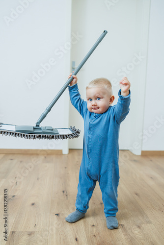 Obraz na płótnie Little boy helper cleaning at home. Blond toddler boy washes the floor with a mop, helping his mother clean at home, free space. Child learns to clean the house. w salonie