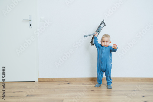 Obraz na płótnie Blond toddler boy washes the floor with a mop, helping his mother clean at home, free space. Child learns to clean the house. w salonie