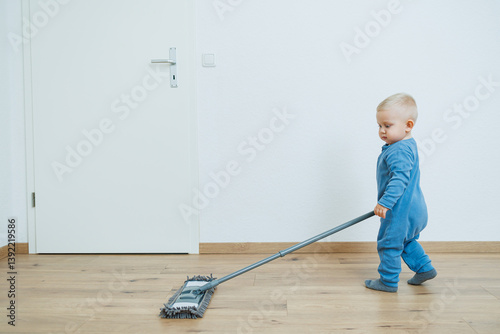Obraz na płótnie Blond toddler boy washes the floor with a mop, helping his mother clean at home, free space. Child learns to clean the house. w salonie