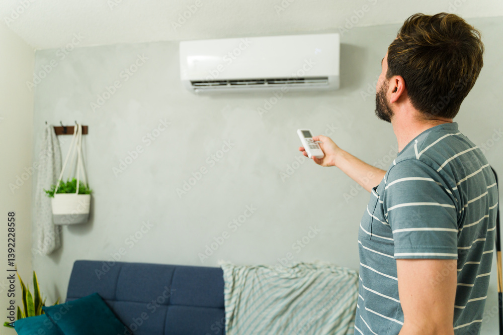 Man adjusting room temperature with air conditioning remote control in summer