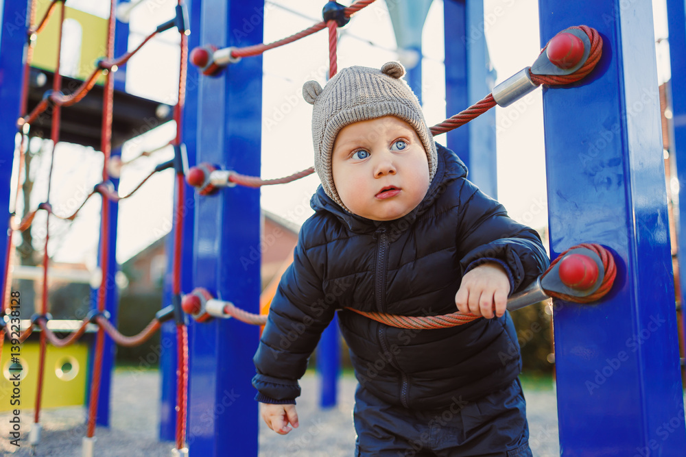 Child walking outdoors. Happy toddler boy on a walk on the playground. Child development, healthy lifestyle of the child. Boy outdoors on an autumn walk. Cheerful boy in the city park.