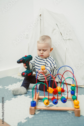 Obraz na płótnie Toys for little children. Toddler boy playing with educational toy. Child playing with toy beads in kindergarten or nursery. Toddler child in nursery. w salonie