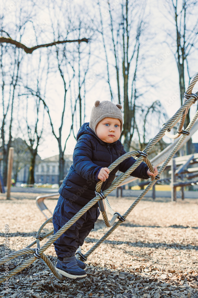 Child walking outdoors. Happy toddler boy on a walk on the playground. Child development, healthy lifestyle of the child. Boy outdoors on an autumn walk. Cheerful boy in the city park.
