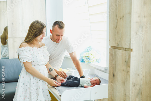 Obraz na płótnie New parents are creating a special bond with their baby in a beautifully bright and modern nursery setting that exudes warmth, affection, and joy as they share loving moments together w salonie