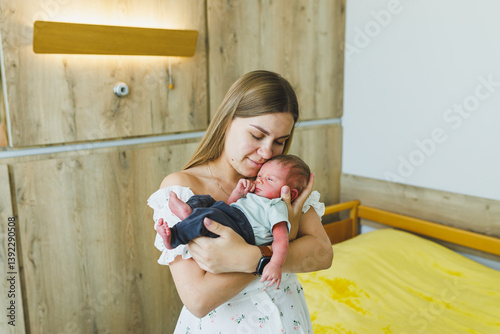 Obraz na płótnie A new mother warmly embraces her precious newborn baby in a bright, cozy, and comforting hospital room, radiating feelings of bliss and love, bonding over their shared joy and warmth w salonie