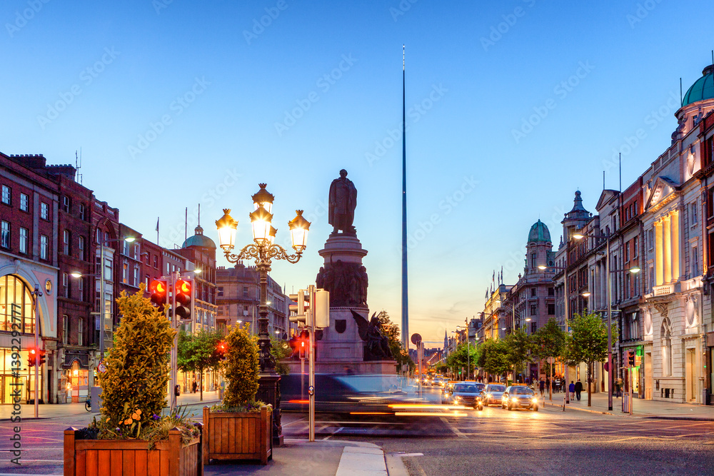 Fototapeta premium O Connell Street in Dublin, Ireland, with historic buildings, the Spire of Dublin, and blurred motion vehicles.