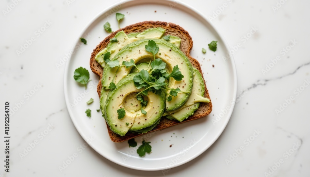 Minimalist top down shot of avocado toast on whole grain bread with microgreens and chili flakes on a white ceramic plate Minimalist top down shot of avocado toast on whole grain bread with microgreens and chili flakes on a white ceramic plate
