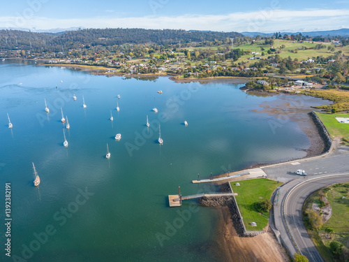 Looking own on yachts anchored in a river near a boat ramp.