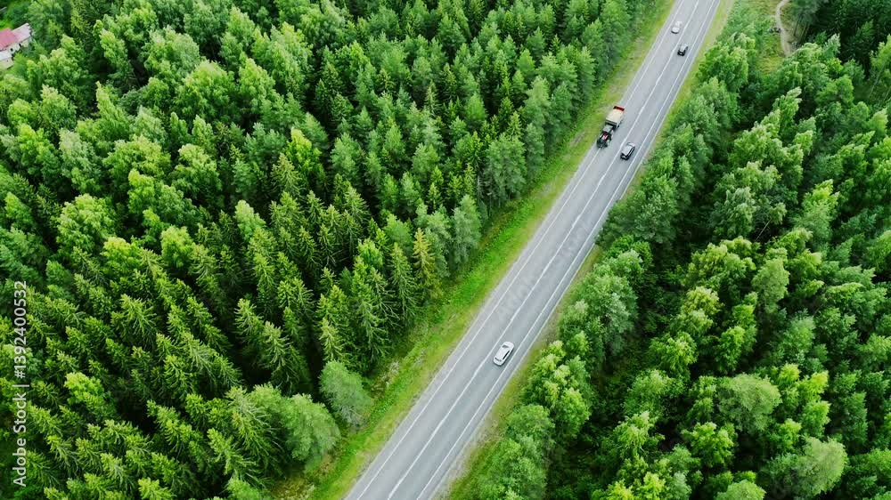 Aerial view of highway road with cars and tractor, green trees summer forests around in Finland, 4k video