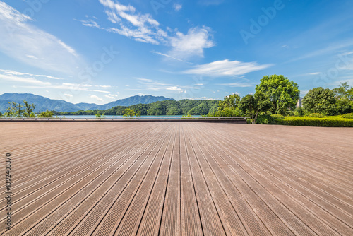 Fototapeta Naklejka Na Ścianę i Meble -  Empty wooden floor platform over lake and mountain landscape with blue sky and cloud background.