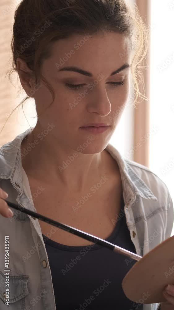 Focused woman painting on canvas in an art studio or workshop, using oil paints to bring artistic inspiration to life. Vertical video. Focused woman painting on canvas in an art studio or workshop, using oil paints to bring artistic inspiration to life. Vertical video.