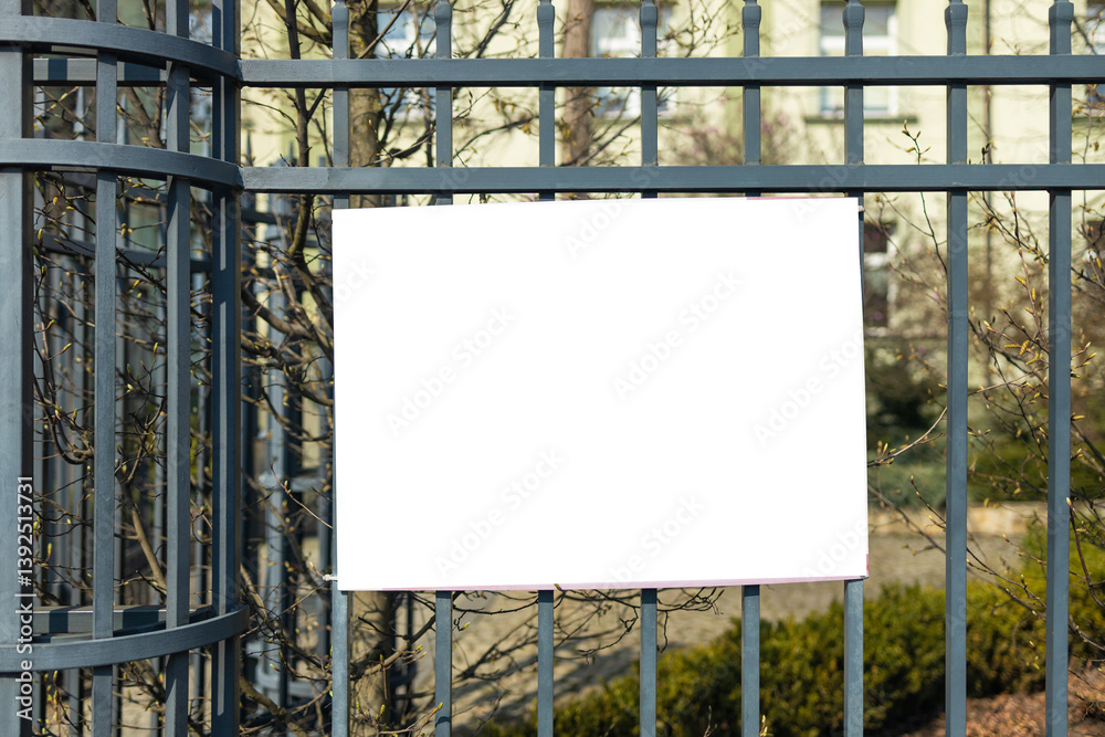 large blank white poster with mockup space hanging on metal fence of play ground outside. High quality photo