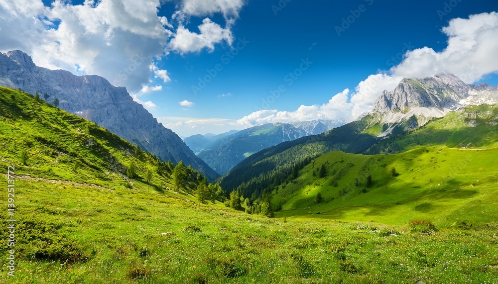 Obraz premium majestic alpine landscape featuring lush green mountains under bright blue sky and soft white clouds on a sunny day