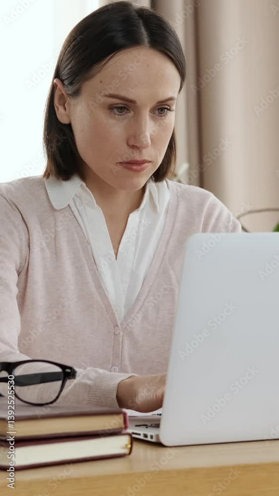 Concentrated office worker is in a home office, working on laptop to develop a strategy and handle accounting tasks. focused and analytical, ensuring business efficiency. Vertical video. Concentrated office worker is in a home office, working on laptop to develop a strategy and handle accounting tasks. focused and analytical, ensuring business efficiency. Vertical video.