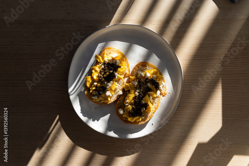 Two slices of bread with scrambled eggs, feta cheese, and truffle paste.