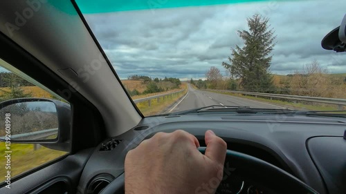Wallpaper Mural Hand holding steering wheel while driving by Scotland roads. Gripping car wheel cruising through scenic Scottish route. Controlling vehicle along countryside road in Scotland. Navigating highway Torontodigital.ca