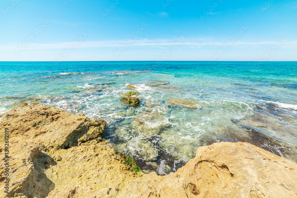 Rocks and turquoise sea in San Giovanni di Sinis beach.