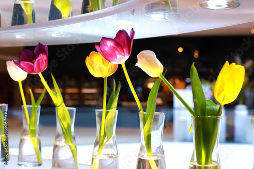 purple and yellow tulips in a decorative vase on a beautiful glass shelf.