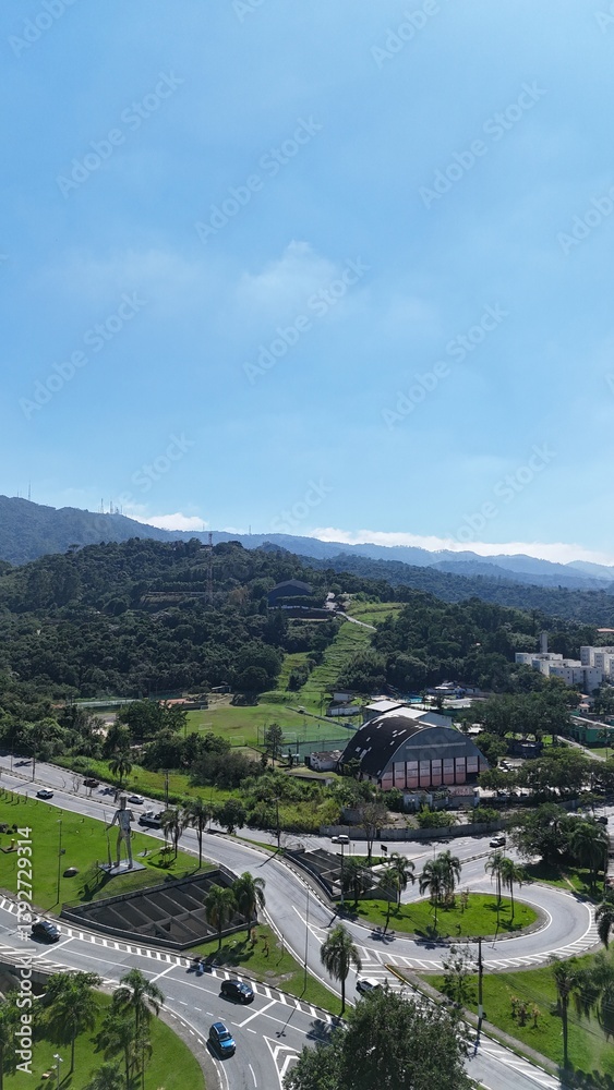 Naklejka premium Foto aérea centralizada de uma rotatória com tráfego urbano sincronizado, ilustrando dinâmica do trânsito e arquitetura viária eficiente