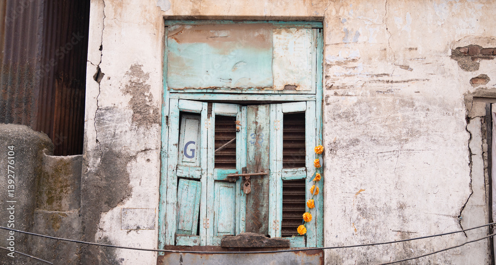 Old house in Mumbai, India, aged rustic facade with broken blue colored window, building with brick and stone Old house in Mumbai, India, aged rustic facade with broken blue colored window, building with brick and stone