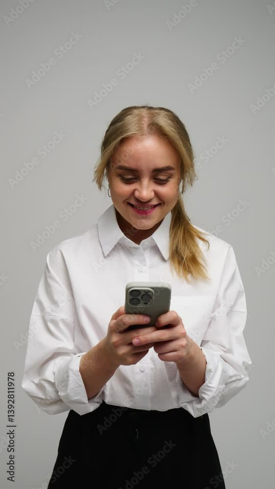 A joyful young woman holds her smartphone, radiating positivity in a contemporary setting. A joyful young woman holds her smartphone, radiating positivity in a contemporary setting.
