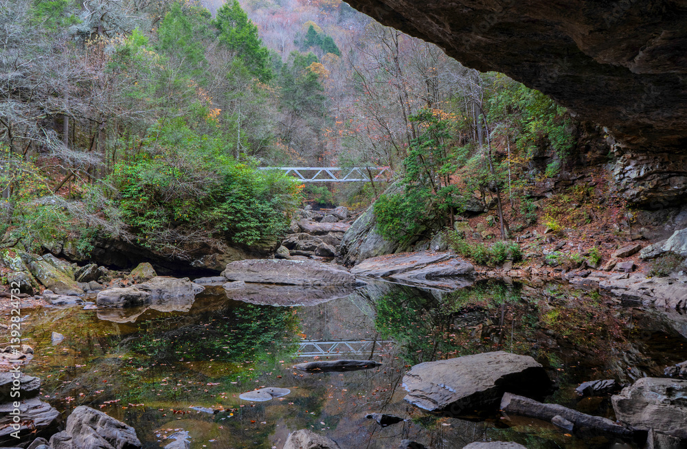 A metal bridge reflected in North Chickamauga Creek Gorge is part of the Cumberland Trail in Tennessee. View from an alcove at the creek crossing. A metal bridge reflected in North Chickamauga Creek Gorge is part of the Cumberland Trail in Tennessee. View from an alcove at the creek crossing.