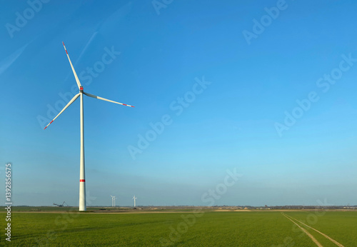 windmill in green field with distant opencast mining excavator concept for energy supply and consumption