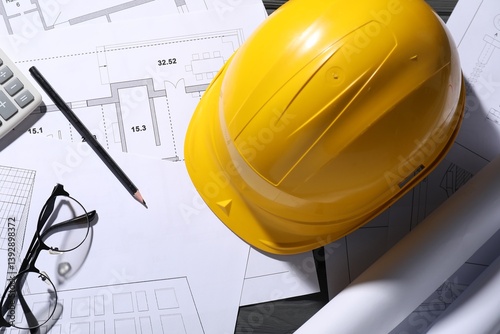 Different architectural drawings, hard hat, pencil and glasses on table, flat lay