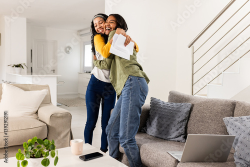Young girl friends hugging joyfully at home, celebrating good news