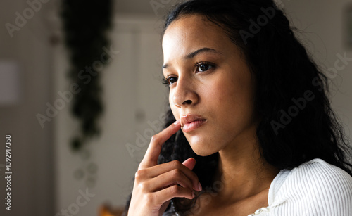 Thoughtful woman at home contemplating ideas with hand on chin, copy space photo