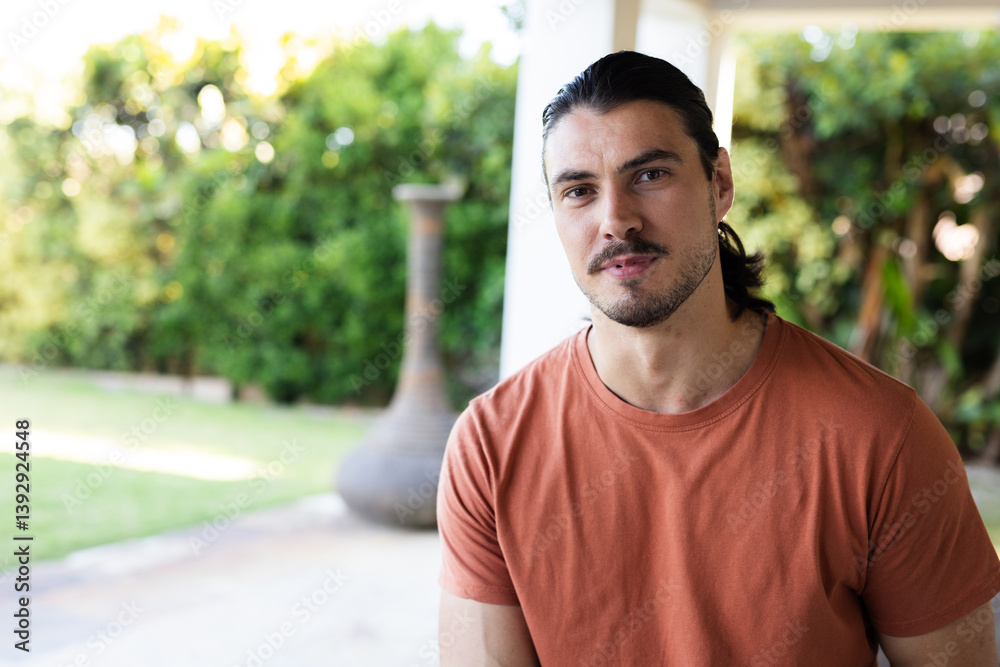 Smiling man in orange shirt enjoying sunny day in garden in garden setting, copy space Smiling man in orange shirt enjoying sunny day in garden in garden setting, copy space