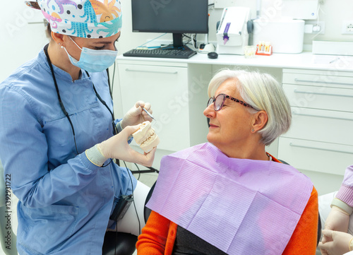 Dentist showing denture model to senior patient in dental clinic