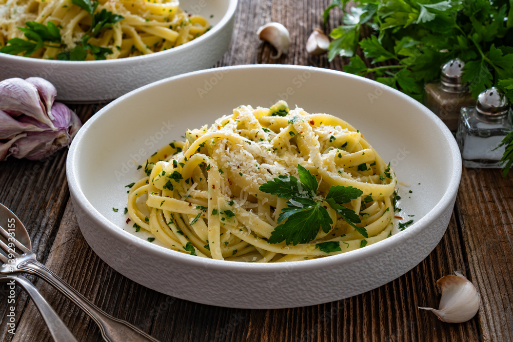 Pasta with garlic and parsley on wooden table. Spaghetti aglio olio on wooden background