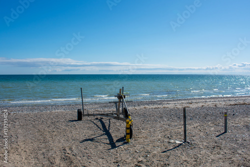 Fototapeta Naklejka Na Ścianę i Meble -  Beach and sea. Boat trailer. Device. Baltic Sea in spring on a sunny day. Sandy beach. Blue sky with clouds. Sports and recreation at sea. Nature.