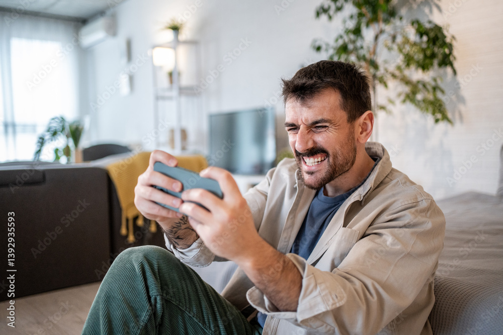 Excited man winning at mobile game at home
