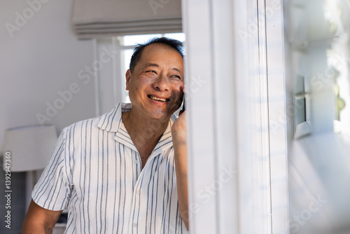 Smiling Senior Asian man talking on smartphone at home, enjoying conversation